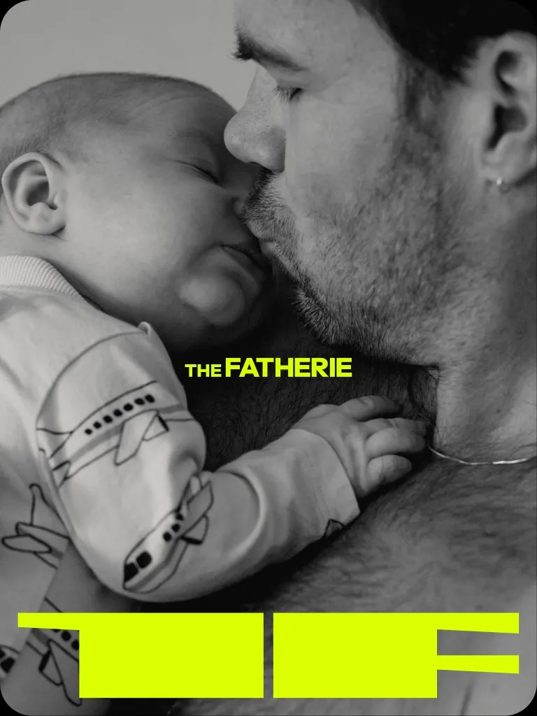 Black and white photograph of a father kissing his sleeping baby